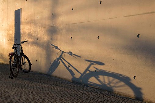 A bicycle leaning against a wall in the golden hour.