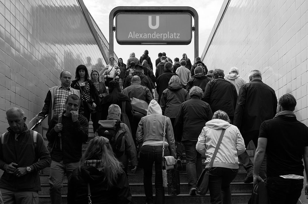 A crowd exiting Alexanderplatz underground station during rush hour.